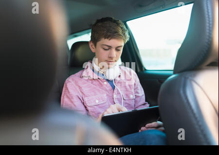 Ragazzo adolescente (16-17) utilizzando la tavoletta digitale in auto Foto Stock