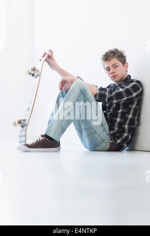 Ragazzo adolescente (16-17) azienda skateboard Foto Stock