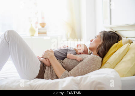 Madre giacente in letto con baby boy (2-5 mesi) Foto Stock