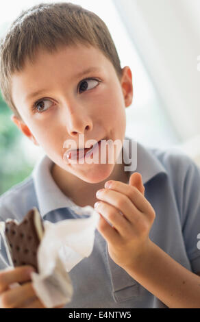 Ragazzo (8-9) a mangiare il gelato a sandwich Foto Stock