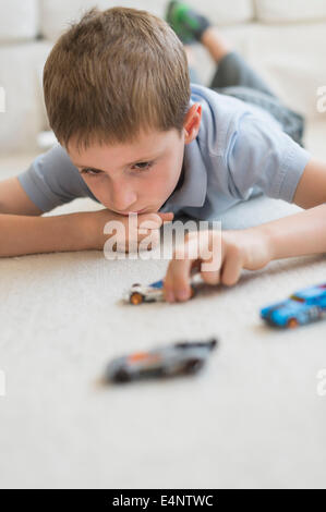 Ragazzo (8-9) giocando con automobili giocattolo Foto Stock