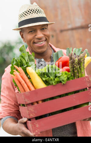 Ritratto di uomo che porta cassetta piena di verdure fresche Foto Stock