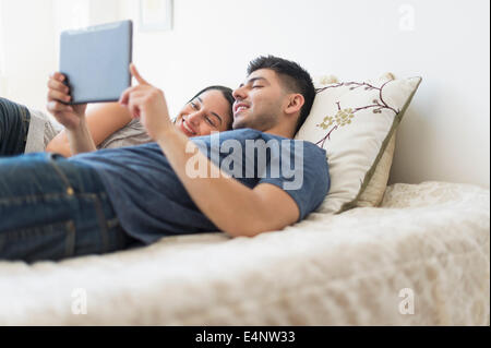 Coppia giovane con tavoletta digitale a letto Foto Stock