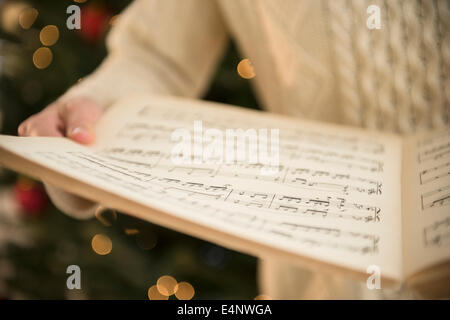 Studio shot di donna holding foglio di musica a natale Foto Stock