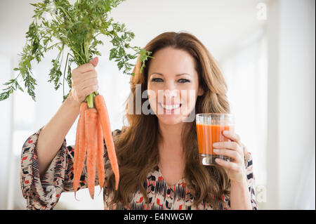 Ritratto di donna che mantiene le carote e succo di carota Foto Stock