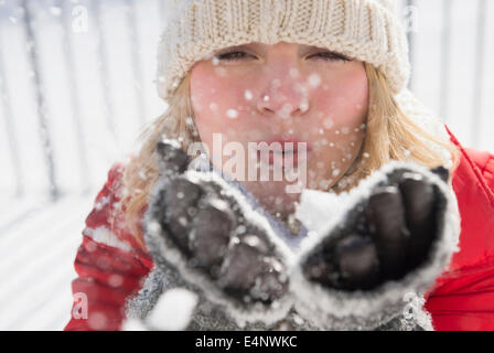 Ritratto di donna che indossa knit hat lavori di soffiaggio della neve Foto Stock