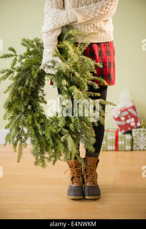 Sezione bassa di donna holding ghirlanda di Natale Foto Stock