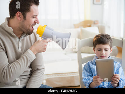 Padre urlando nel megafono per la disciplina del figlio (8-9) Foto Stock