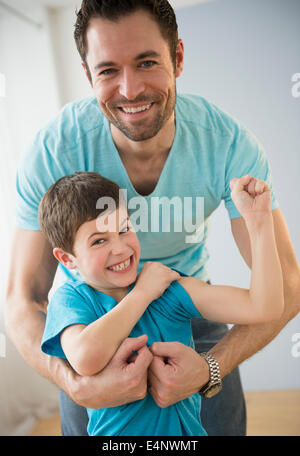 Padre abbracciando il figlio (8-9), ragazzo flettendo i muscoli