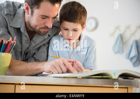 Padre aiutando il suo figlio (8-9) con i compiti Foto Stock