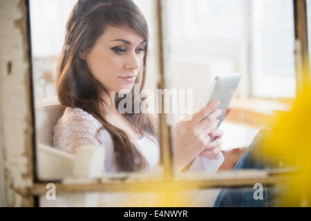 Giovane donna con tavoletta digitale in salotto Foto Stock