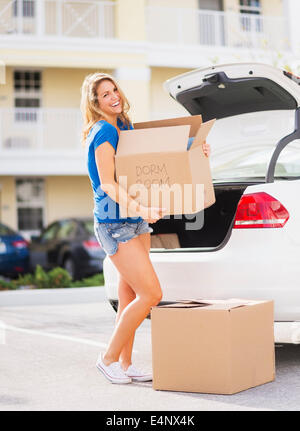 Stati Uniti d'America, Florida, Giove, giovane donna portando scatola dalla vettura nella sua nuova casa Foto Stock
