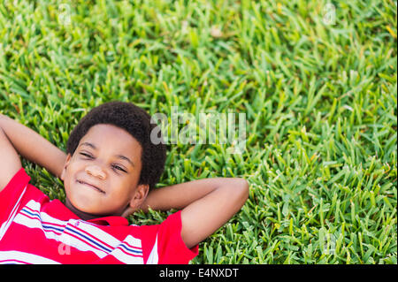 Ragazzo (6-7) giacenti sull'erba Foto Stock