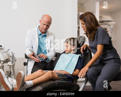 Dentista holding tavoletta digitale con paziente (12-13) x-ray Foto Stock