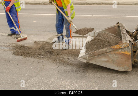 Lavoratore di asfalto di funzionamento durante la costruzione di strade e lavori di riparazione Foto Stock