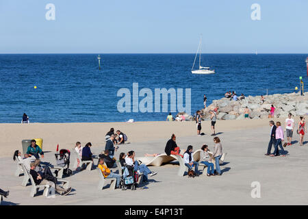 Le persone che si godono la giornata di sole sul lungomare di Barceloneta a Barcellona, in Catalogna, Spagna. Foto Stock