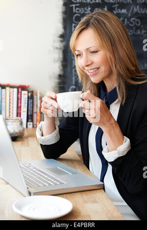 Imprenditrice utilizzando laptop in Cafe Foto Stock