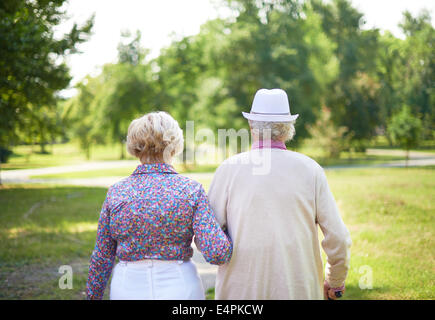 Vista posteriore di serena coppia senior facendo una passeggiata nel parco Foto Stock