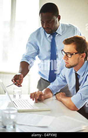Immagine di due giovani imprenditori utilizzando laptop e interagire in riunione Foto Stock
