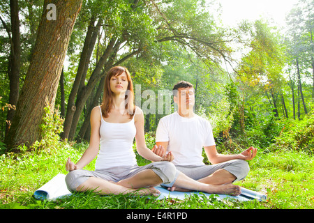 Giovane uomo e donna fare yoga in giardino Foto Stock