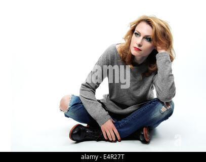 Pensando donna seduta sul pavimento isolato su sfondo bianco. Foto Stock