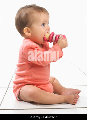 Baby girl (8 mesi) con il giocattolo in bocca Foto Stock