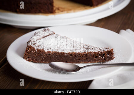 Cioccolato artigianale blackout torta con un pezzo tagliato al buio su un tavolo di legno Foto Stock