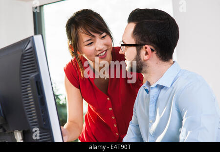 Close-up del giovane imprenditore e giovane imprenditrice avente una discussione di fronte a un computer in ufficio, Germania Foto Stock