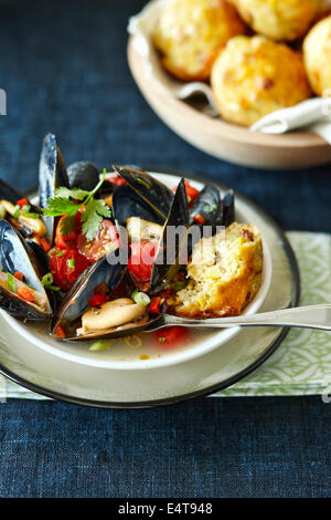 Unico che serve di cotto di cozze fresche con pomodori, cipollotti, peperoni rossi e il coriandolo con il pane di mais Foto Stock