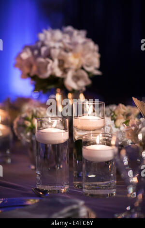Close-up di candele galleggianti in vetro portacandele sul tavolo della reception, con composizioni floreali in background, Canada Foto Stock