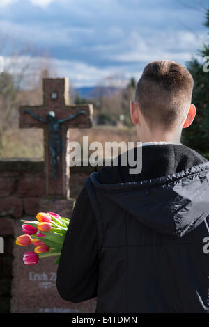 Adolescente in piedi di fronte a gravi pietre nel cimitero Foto Stock