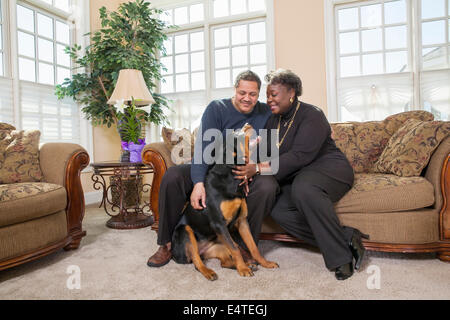 Coppia Matura Petting cane nel salotto di casa Foto Stock