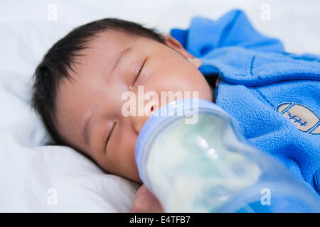 Close-up di due settimane vecchio Asian Baby girl dormendo mentre bere dalla bottiglia, studio shot Foto Stock