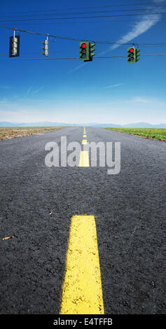 Vista ravvicinata di giallo, rotture di linea centrale sulla autostrada deserta, con il rosso semaforo appeso su fili attraverso strada, Canada Foto Stock