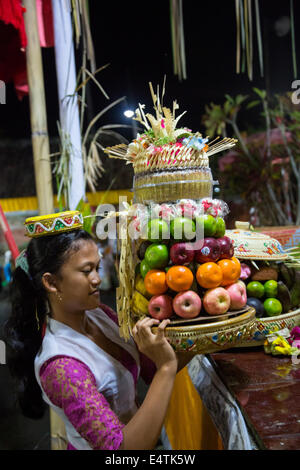 Bali, Indonesia. Giovane donna Indù collocando un offerta al tempio nella speranza di un buon raccolto di riso. Foto Stock