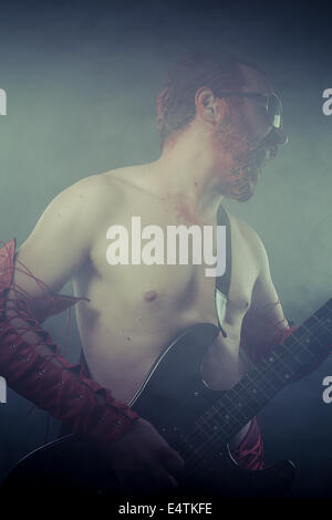 Pesante, uomo a bilanciere con una chitarra elettrica in un concerto rock Foto Stock