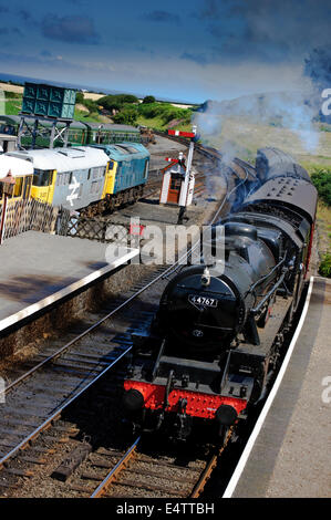 Treno a vapore in arrivo sulla linea di papavero a Weybourne stazione ferroviaria in North Norfolk con vedute della Costa North Norfolk. Foto Stock