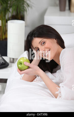 Donna di mangiare un apple sul suo allenatore Foto Stock