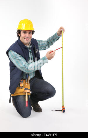 Tradesman utilizzando un nastro di misurazione Foto Stock