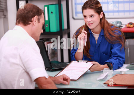 Femmina con apprendista idraulico in ufficio Foto Stock