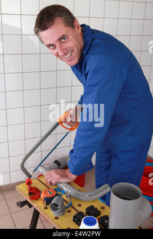 Sorridente plumber segatura di tubo in plastica Foto Stock