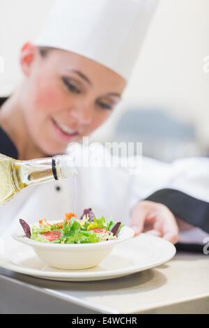 Lo Chef versando olio d'oliva sull'insalata Foto Stock