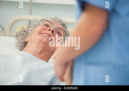 Paziente anziano che guarda l'infermiera Foto Stock