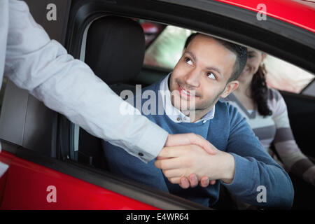 L'uomo agitando la mano di un rivenditore di auto Foto Stock