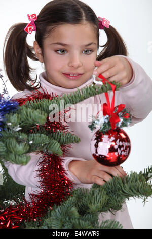 Ragazza giovane decorare un albero di Natale Foto Stock