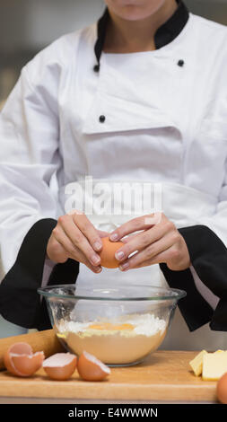 Chef uovo di cracking in tazza di farina Foto Stock