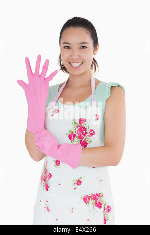 Donna mettendo su guanti di plastica Foto Stock