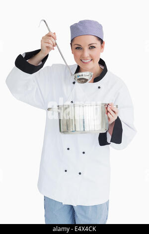 Felice cook che serve con un mestolo e una pentola Foto Stock