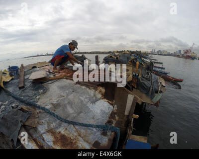 Manila, Filippine. 17 Luglio, 2014. Un uomo che ripara il tetto della sua casa dopo che è stato danneggiato dal tifone Rammasun presso una delle baraccopoli di Manila, Filippine, il 17 luglio 2014. Il tributo di morte pagato typhoon Rammasun è salito a 38, il locale disastro Agency ha detto giovedì. Il disastro nazionale di riduzione dei rischi e di Consiglio di Gestione (NDRRMC) detto il tifone anche lasciato 10 feriti mentre altri otto sono state dichiarate mancanti. Credito: Rouelle Umali/Xinhua/Alamy Live News Foto Stock