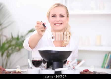 Donna avente una Fondue bourguignonne Foto Stock